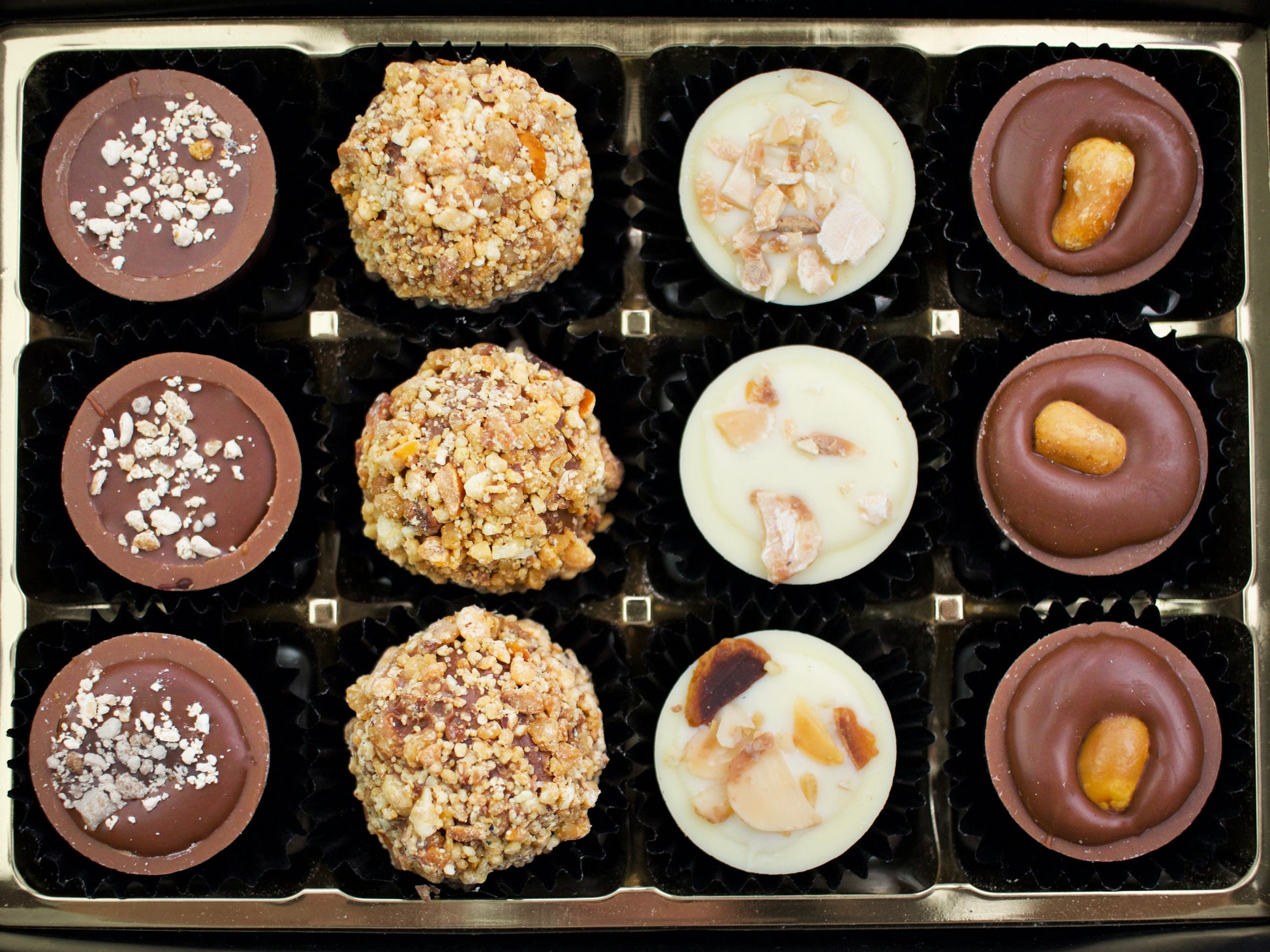 image shows a selection of 12 nut butter and caramel filled chocolates