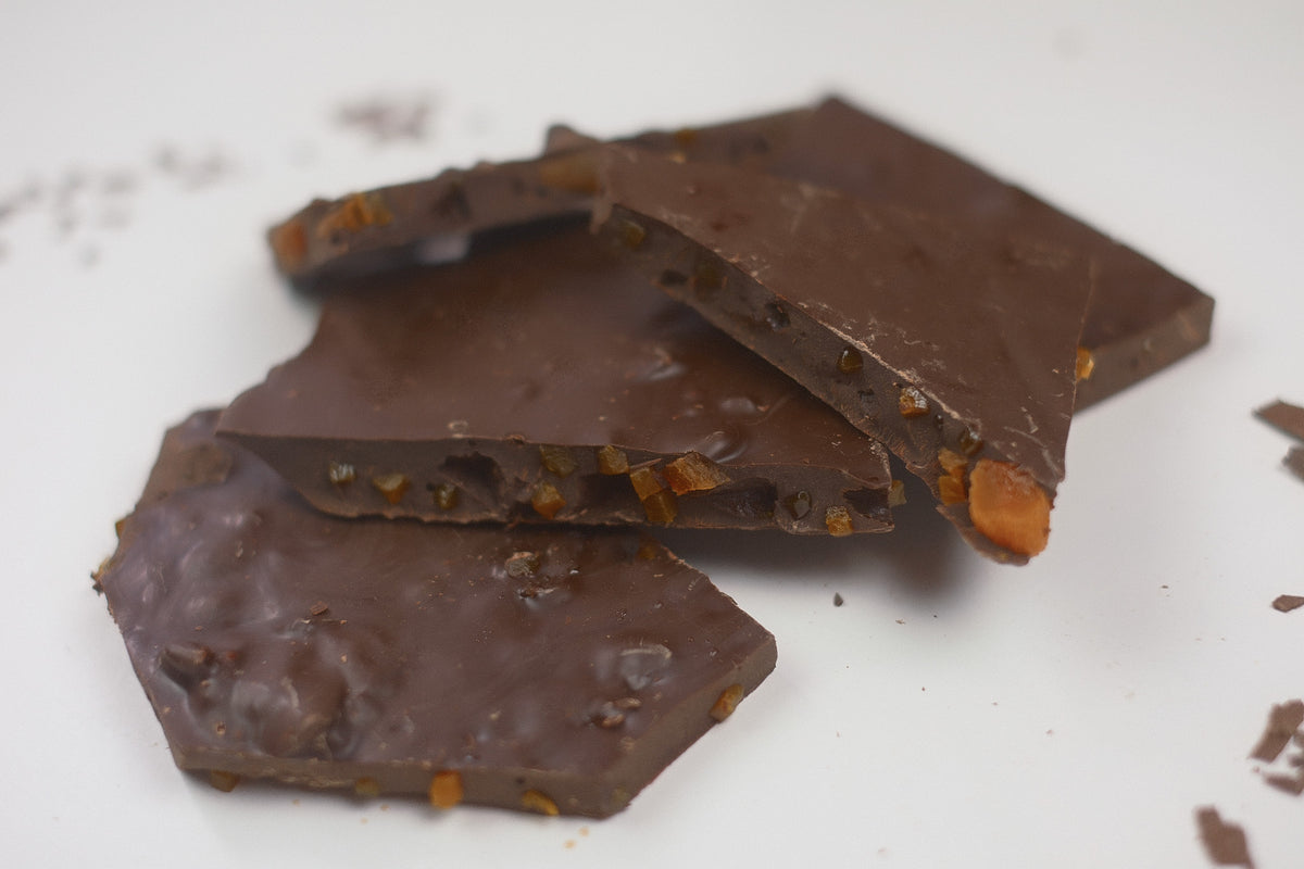 Chocolate bark pieces with visible orange and nut inclusions, arranged on a plain white surface.