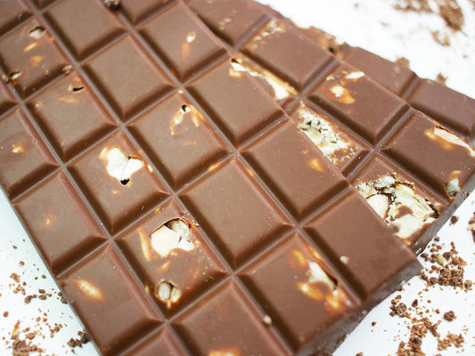 Image shows close up of 100g milk chocolate bars embedded with toasted almonds.