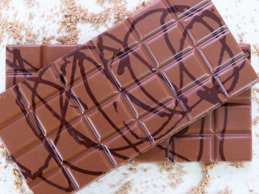 image shows a close up of two 100g hand made sugar free orange flavour bars drizzled with milk chocolate.