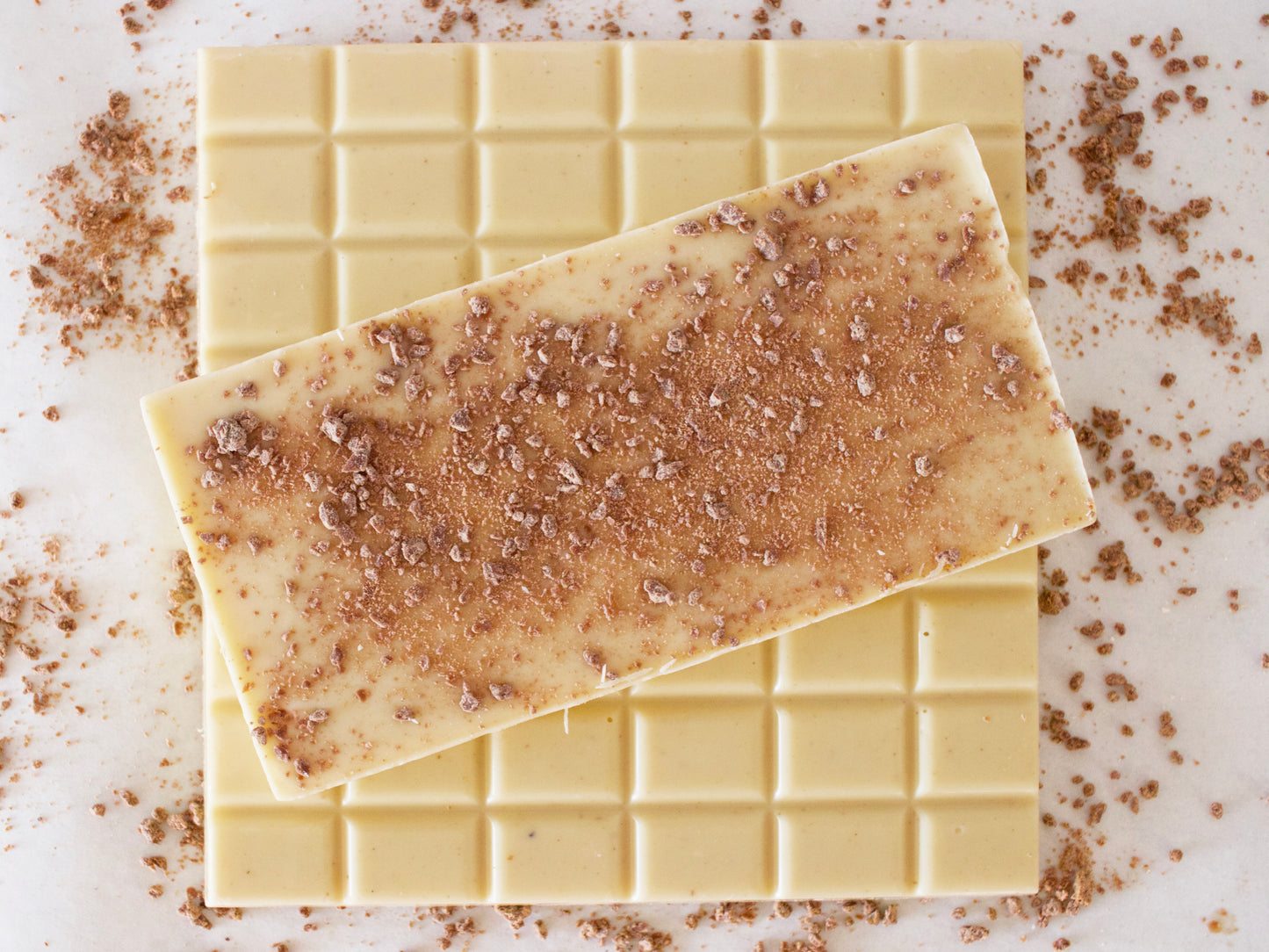 image shows 3, 100g white vanilla chocolate bars, with one side sprinkled with milk chocolate crumb.