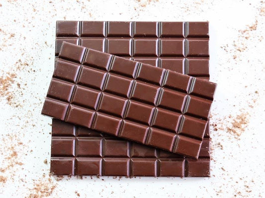 Image shows a pile of 3, 100g 54% cocoa hand made chocolate bars.