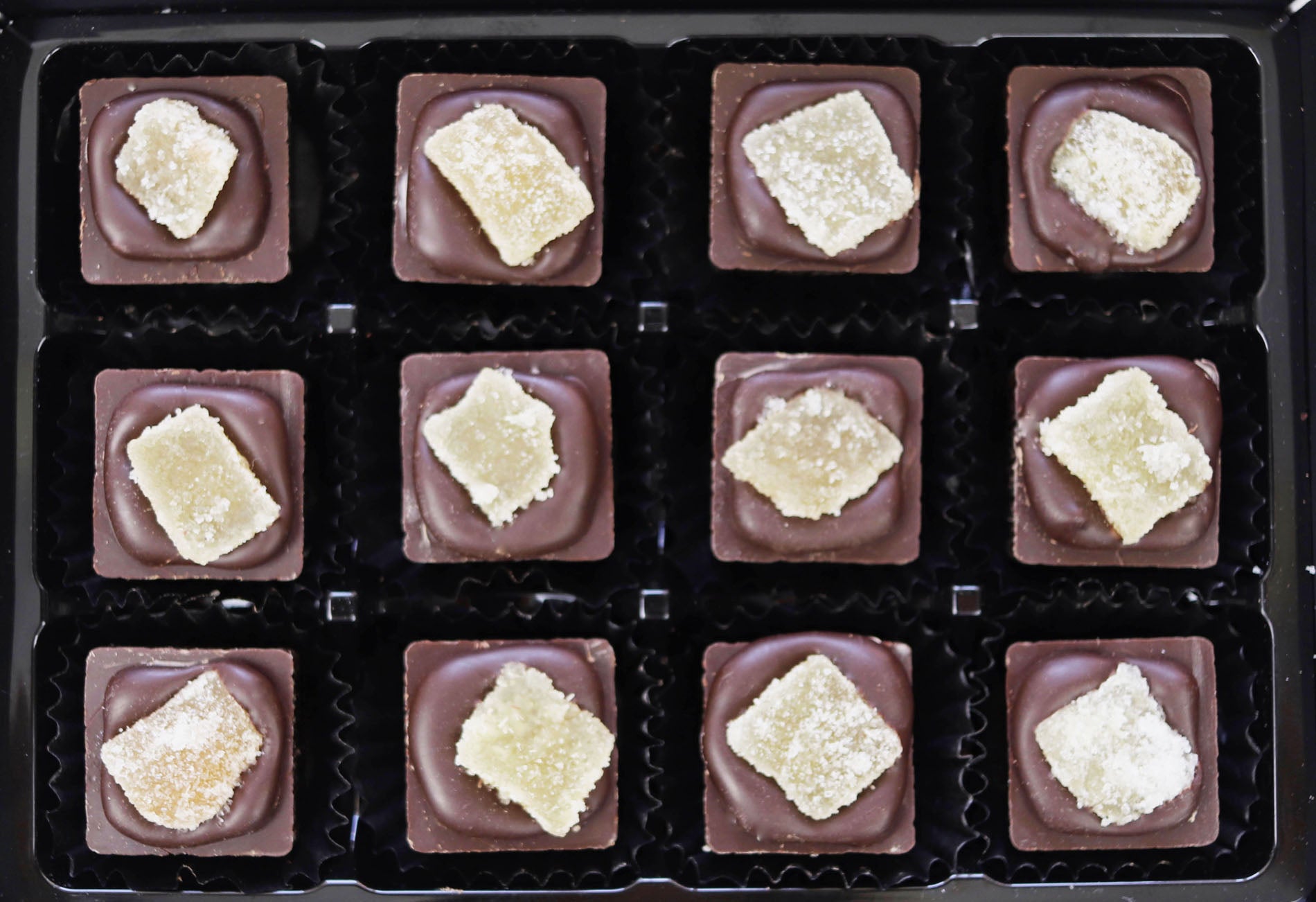 Image shows a gift box of 12 hand made dark, ginger cream filled chocolates, topped with crystallised ginger.