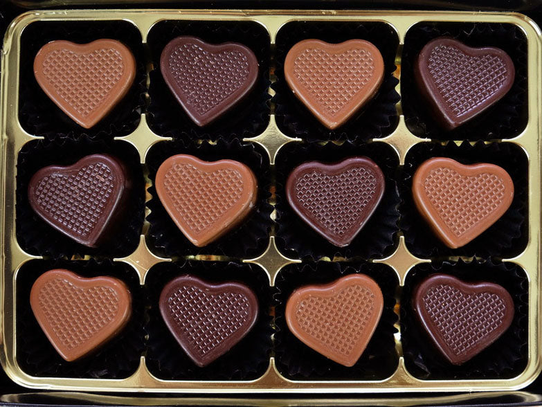 Image shows a gift box of 6 milk and 6 dark hand crafted chocolate hearts that are filled with caramel.