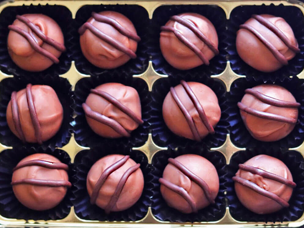 Image shows a box of 12 hand made Intense Orange Chocolate Truffles. Great Taste Award winners. 
