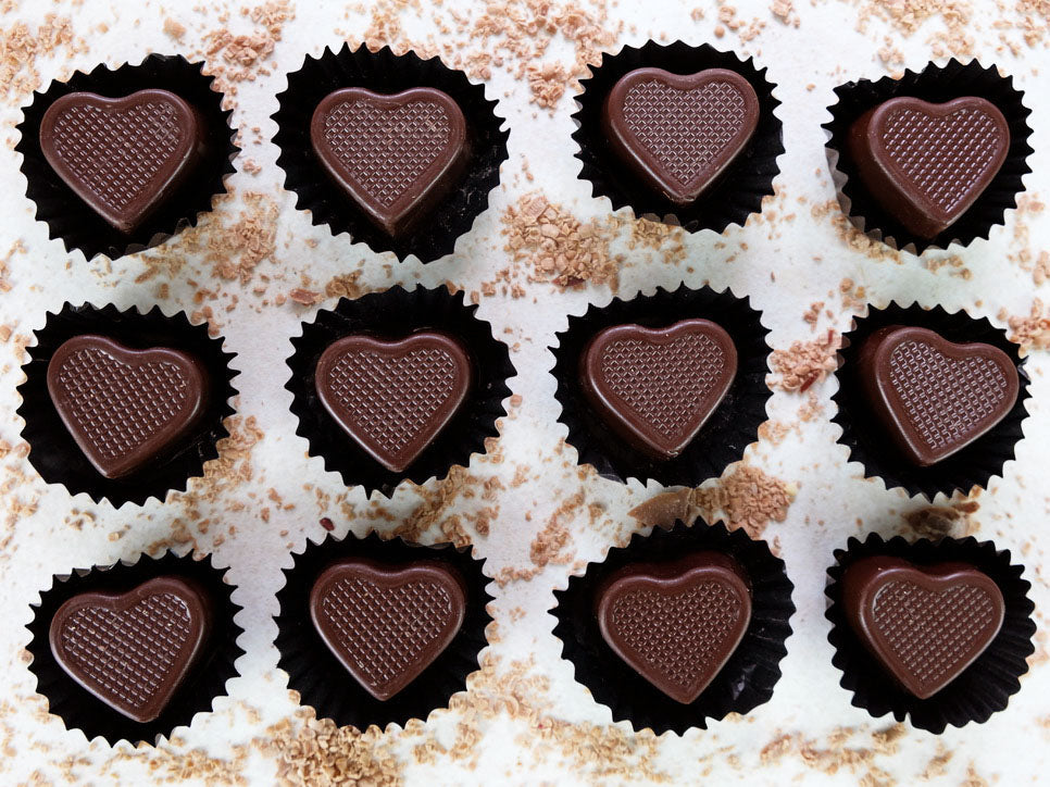 Image shows 12 hand crafted heart shaped dark chocolates that are filled with caramel.