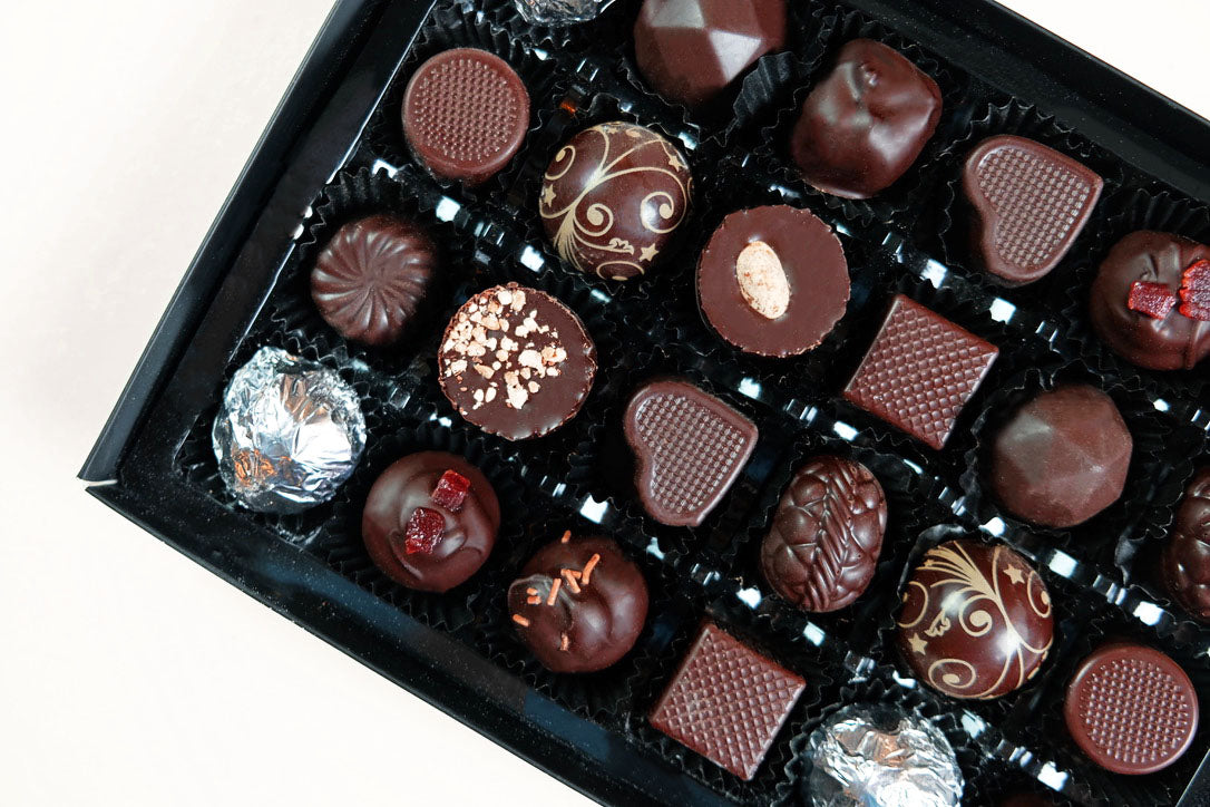 image shows a selection of vegan dark chocolates available in 3 box sizes
