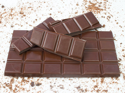 image shows a 100g vegan milk chocolate bar with broken pieces of bar on top