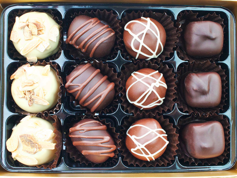 image shows a box of 12 vegan white, milk and dark marzipan chocolates.